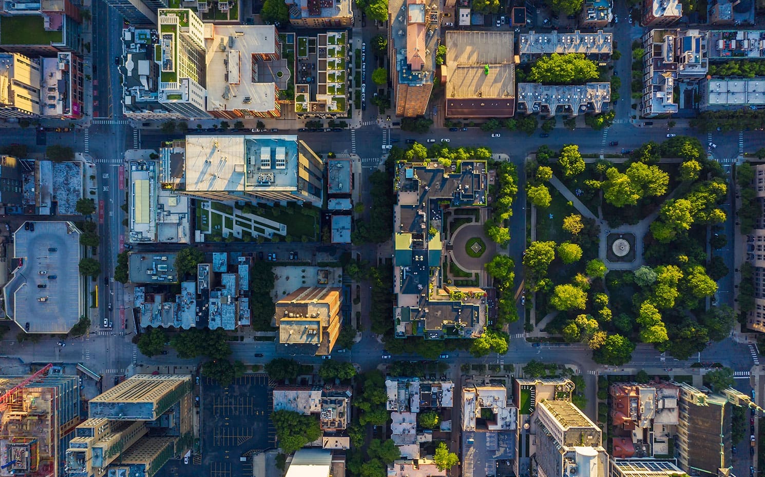Bird's-eye view of cityscape. Buildings, busy streets, trees, and a park.