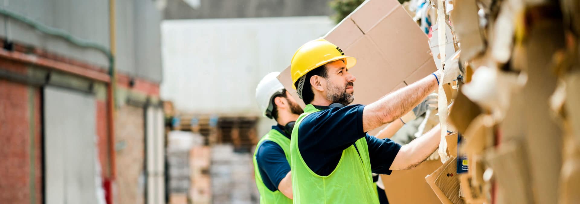 Two waste management workers sorting cardboard in an alleyway