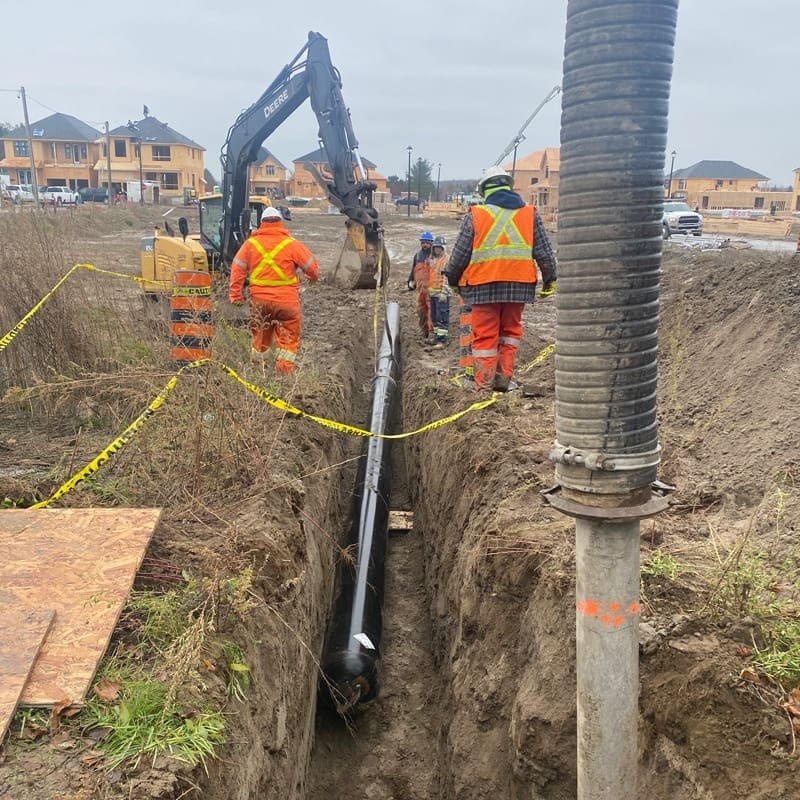a 12" steel encasement in a trench with workers walking beside the trench
