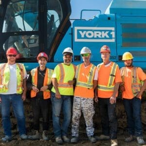 Group of York1 employees standing together in front of York1 equipment.