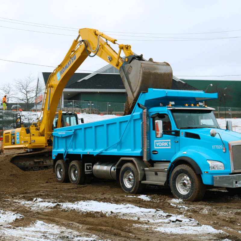 YORK1 excavator loading excess soil into a blue dump truck