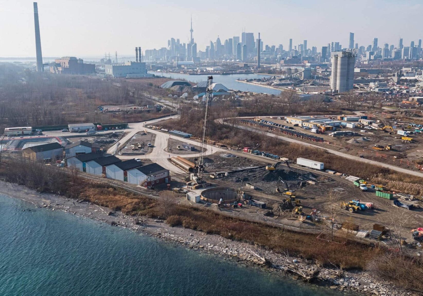 Overhead shot of job site at Ashbridges Bay. Lake in foreground, cityscape in background.